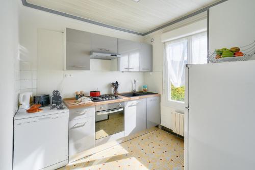 une cuisine blanche avec des armoires blanches et une fenêtre dans l'établissement 400m de la plage - maison pour 6 personnes, au Guilvinec