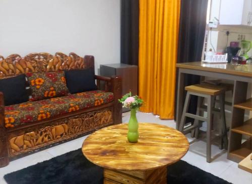 ein Wohnzimmer mit einem Sofa und einem Tisch mit einer Vase darauf in der Unterkunft Vizuri Hideout in Kampala