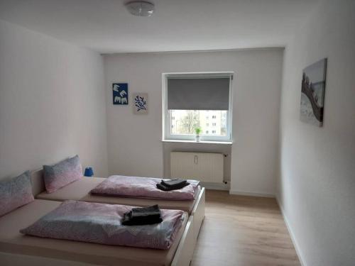 two beds in a white room with a window at Wohnung mit Balkon in Fürth in Fürth
