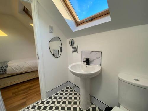 a bathroom with a sink and a toilet and a window at Stylish 3-Bed House with Free Parking & Netflix by HP Accommodation in Northampton