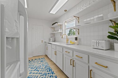 uma cozinha branca com armários brancos e um tapete azul em Selah Cottage em Gulf Shores
