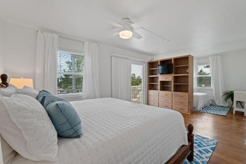 een witte slaapkamer met een groot bed met blauwe kussens bij Selah Cottage in Gulf Shores