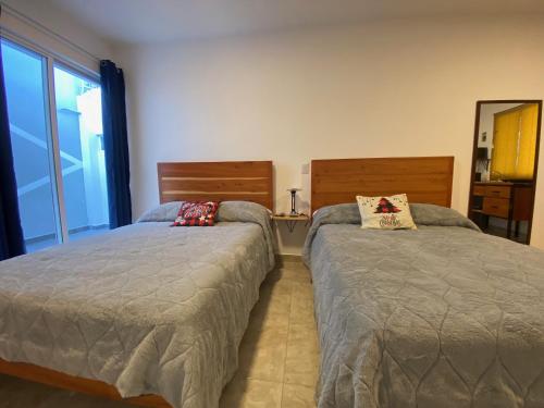 1 Schlafzimmer mit 2 Betten und einem Spiegel in der Unterkunft KC Hotel & Suites in Comitán de Domínguez