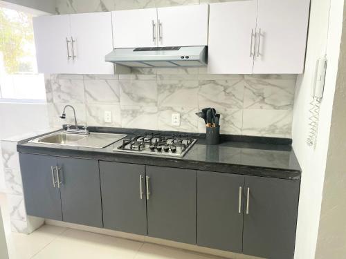 a kitchen with white cabinets and a stove and a sink at Suite Jacarandas 103 in Guadalajara