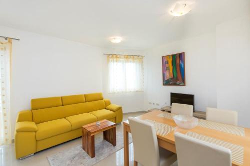a living room with a yellow couch and a table at House ALANIS wtih sea view in quiet location in Ravni