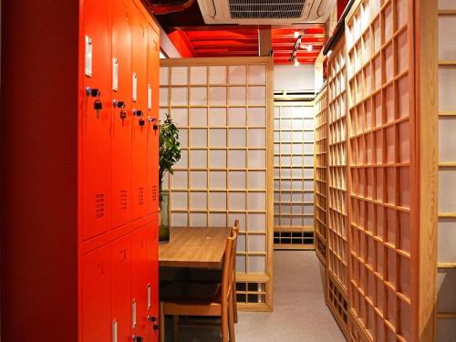 a room with a table and a room with wooden lockers at KOBE coffee hostel in Kobe