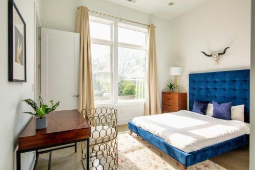 1 dormitorio con cama azul, escritorio y ventana en 2 Lux Homes with Rooftop Views Sleeps 24, en Nashville