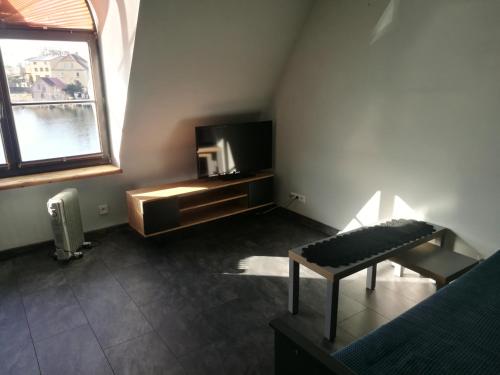 a living room with a tv and a bench and a window at Apartamenty Sielawa in Mikołajki
