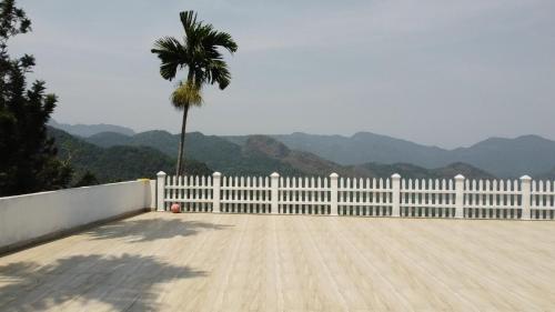 a white fence with a palm tree and a basketball at Serenity Valley Ambuluwawa Resort in Kandy