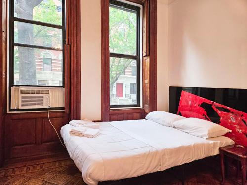 a bed in a room with two windows at Entire floor in a charming townhouse in New York