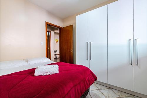 - une chambre avec un lit doté d'une couverture rouge et de placards blancs dans l'établissement Apto pé na areia vista mar em Meia Praia EVB308, à Itapema