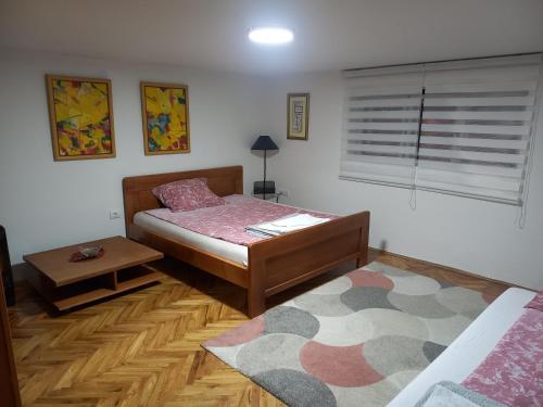 1 dormitorio con cama, mesa y alfombra en Stan na dan Kamenički park, en Sremska Kamenica