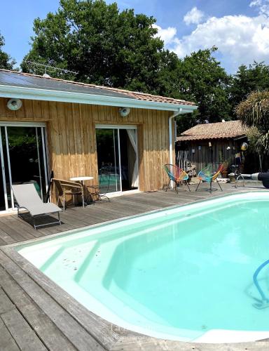 une piscine avec des chaises et une maison dans l'établissement Maison bois flotté, à Lège-Cap-Ferret