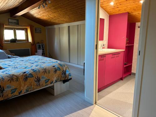 a bedroom with a bed and a kitchen with pink cabinets at LES JARDINS DE CARIBOLE in Fourneaux