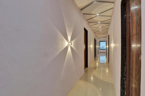 a hallway with a wall light on a white wall at Vr Hotel in Surat