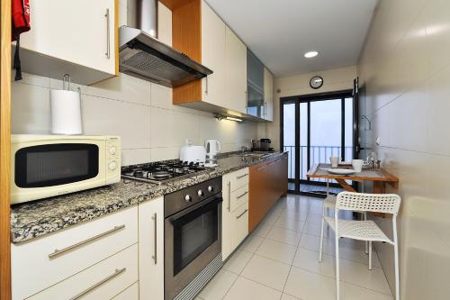 a kitchen with a stove and a microwave at Oeiras by the beach - Checkinhome in Oeiras