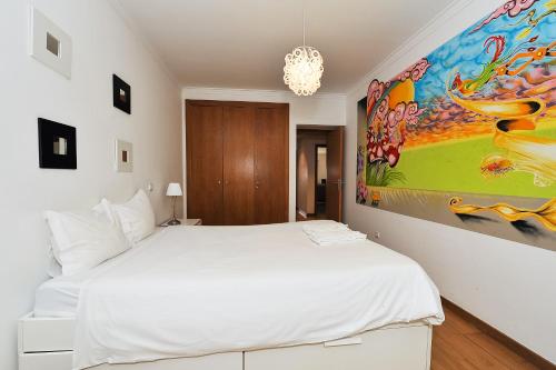 オエイラスにあるOeiras by the beach - Checkinhomeの白いベッドと壁に絵画が飾られたベッドルーム1室