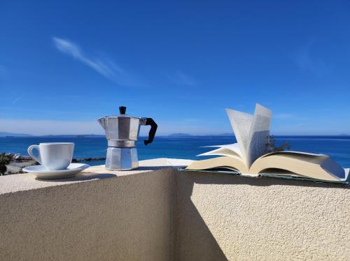 蒂雷納自由鎮的住宿－Appartamenti Vacanze Villa Meo，坐在带咖啡壶和杯子的树 ⁇ 上的一本开放式书