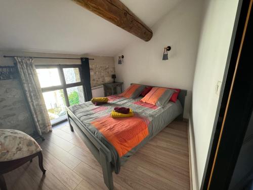1 dormitorio con 1 cama con edredón de naranja y ventana en Petite maison sur jardin secret, en Aviñón