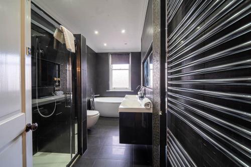 a bathroom with a tub and a toilet and a sink at Bannerdale Villa - Sheffield in Sheffield