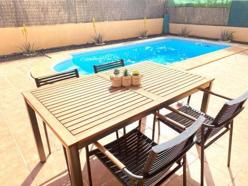 a wooden table and chairs next to a swimming pool at Villa Marlau con piscina privada in La Oliva