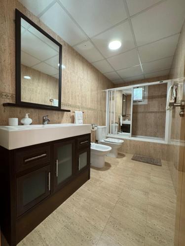 a bathroom with a sink and a toilet and a mirror at Apto. Cullera vistas espectaculares primera línea in Cullera