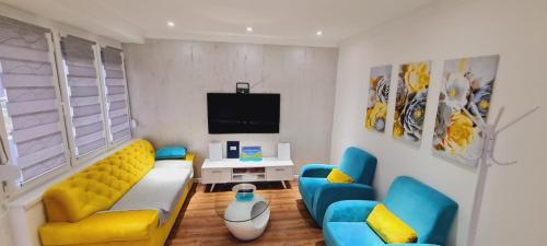 uma sala de estar com mobiliário azul e amarelo e uma televisão em LARA S em Banja Luka