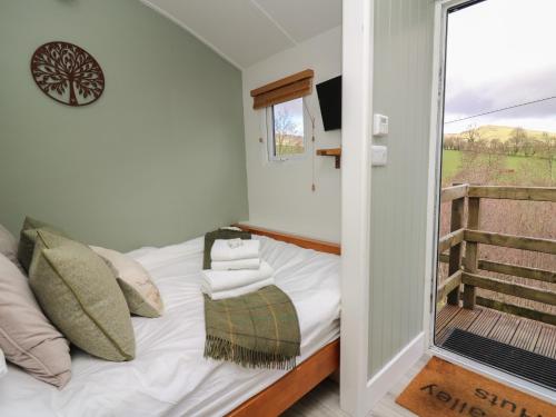 a small bedroom with a bed and a balcony at Cuckoo at Wild Valley Huts in Oswestry