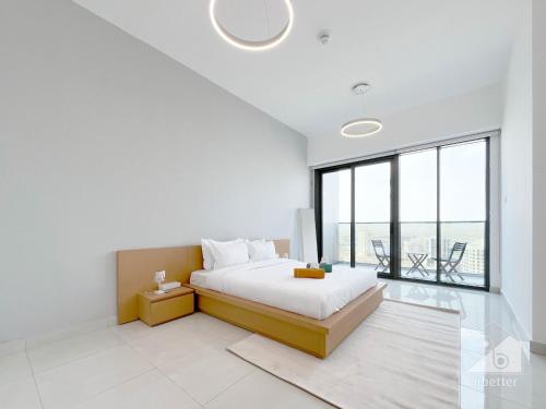 a white bedroom with a bed and a large window at NEW!Luxury 1B with balcony in Blue Wave Tower Dubai in Dubai