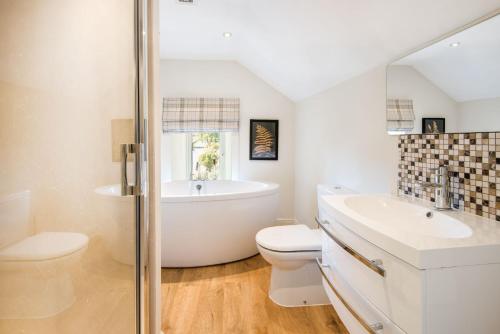 uma casa de banho com uma banheira, um WC e um lavatório. em Woodcroft Cottage em Richmond