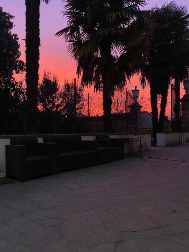 a sunset with palm trees and a bench in a park at LA GASTALDIA in Pontecasale