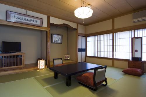 een kamer met een tafel en stoelen en een televisie bij Ekinariya Ryokan in Kusatsu