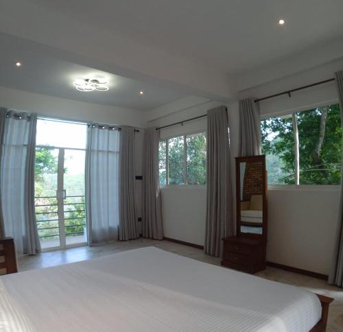 a bedroom with a large bed and large windows at Sithara Estate Bungalow in Ella