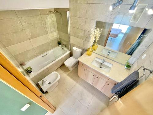 a bathroom with a sink and a toilet and a tub at Apto de diseño Salou-piscina gym in Salou