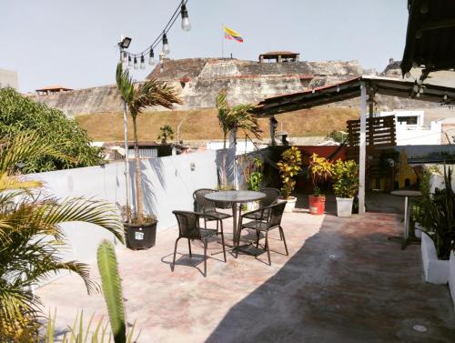 d'une terrasse avec une table, des chaises et des palmiers. dans l'établissement Del Castillo Mirador Hostel, à Carthagène des Indes
