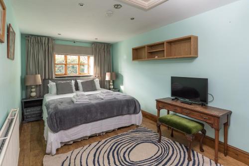 a bedroom with a bed and a desk with a television at East Wing in Bristol