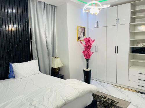 Un dormitorio con una cama blanca y un jarrón con flores rosas en WHITEFIELD LUXURY APARTMENT, en Orimedu