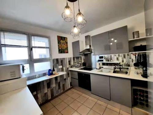 une grande cuisine avec des placards blancs et un évier dans l'établissement Le Sensation - En plein coeur de ville- ascenseur, à Nîmes