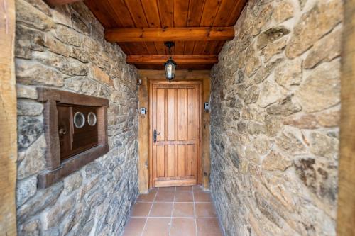 a hallway with a stone wall and a wooden door at Posada El Aprisco Manjirón in Manjirón