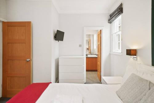 sypialnia z białym łóżkiem i czerwonym kocem w obiekcie Chelsea Diamond w Londynie