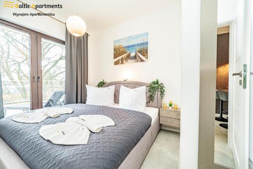 a bedroom with a bed with two towels on it at Baltic Apartments - Kormoran in Świnoujście