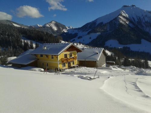 a yellow house in the snow with mountains at Appartement Reitlhof, Bio Berg Bauernhof in Krispl