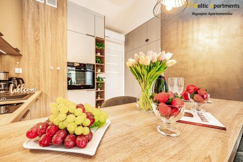 a table with a bunch of fruit and flowers on it at Baltic Apartments - Kormoran in Świnoujście