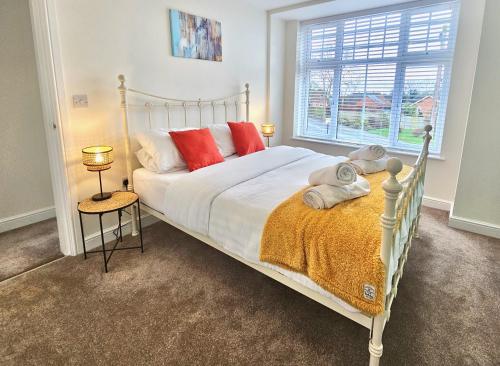a bedroom with a white bed with red pillows and a window at Cosy yet spacious, 3BR, Parking, Village Location in Oswestry