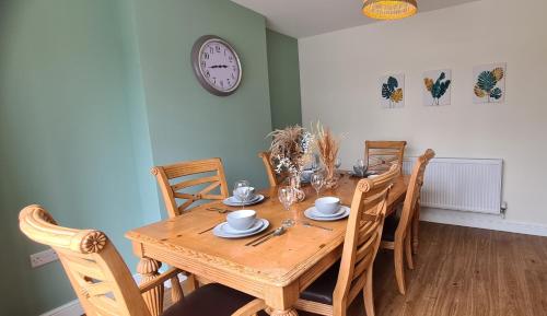 a dining room table with chairs and a clock on the wall at Cosy yet spacious, 3BR, Parking, Village Location in Oswestry
