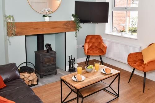 a living room with a fireplace and orange chairs at Cosy yet spacious, 3BR, Parking, Village Location in Oswestry