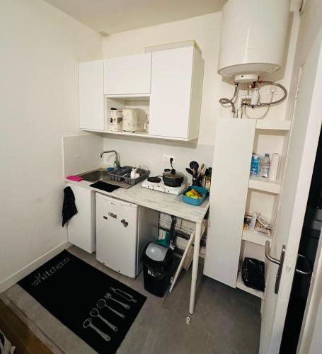 une petite cuisine avec des armoires blanches et un évier dans l'établissement Studio Agréable, à Issy-les-Moulineaux