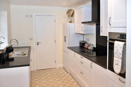 a kitchen with white cabinets and a black counter top at Cosy yet spacious, 3BR, Parking, Village Location in Oswestry