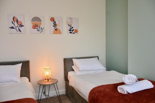 a bedroom with two beds and a table with a lamp at Cosy yet spacious, 3BR, Parking, Village Location in Oswestry