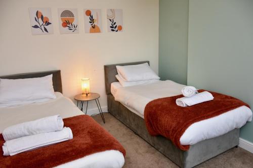 a bedroom with two beds and a table with a lamp at Cosy yet spacious, 3BR, Parking, Village Location in Oswestry